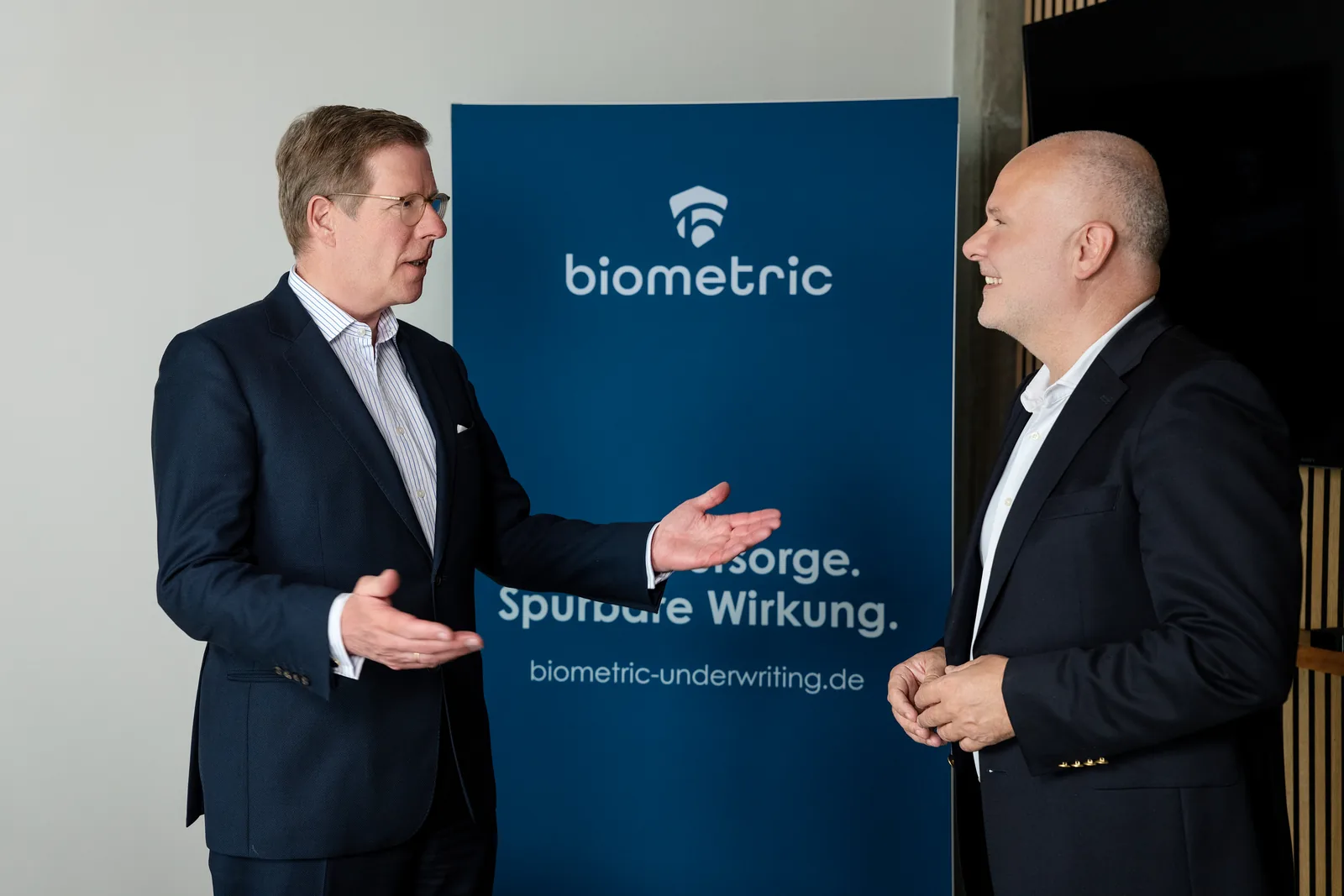 Daniel Horenburg im Beratungsgespräch vor einem Aufsteller von biometric underwriting